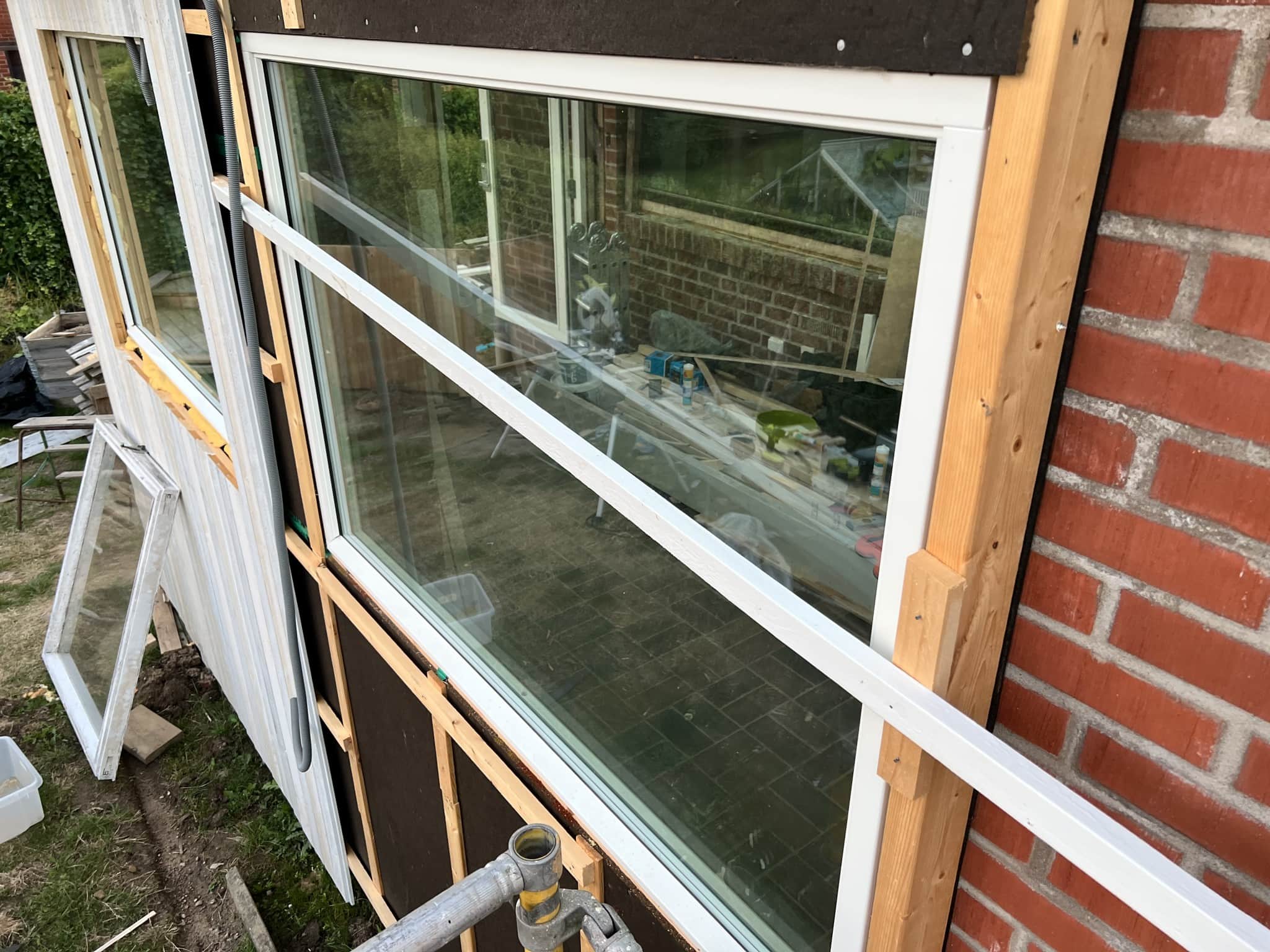 Renovering av fönster med synliga trästommar och verktyg i bakgrunden, vilket visar på pågående inrednings- och renoveringsarbete.