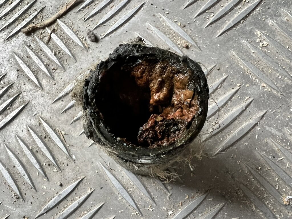 En rostig, sliten koppling på en räfflad metallplatta, vilket antyder behov av reparation eller utbyte under renoveringsarbetet.