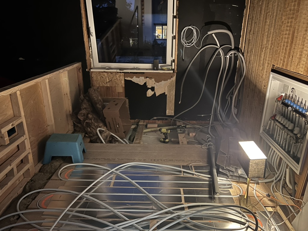 Rörigt barnrum under renovering med ledningar och material synliga.